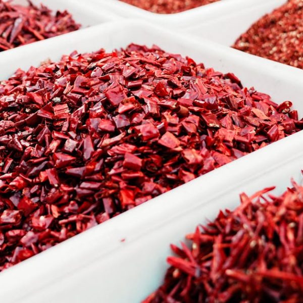 Close-up view of vibrant red dried chili peppers in bins at an outdoor market.