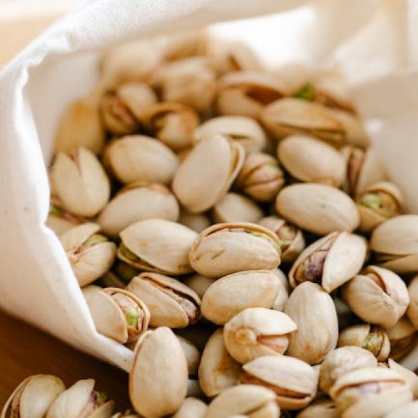 A close-up image of pistachios spilling out of a reusable eco bag on a table.