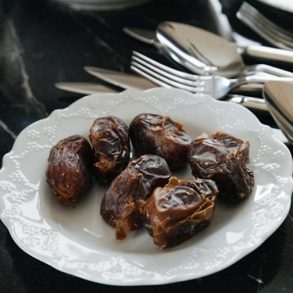 A stylish still life of dates on a white plate with cutlery, perfect for Ramadan or dessert themes.
